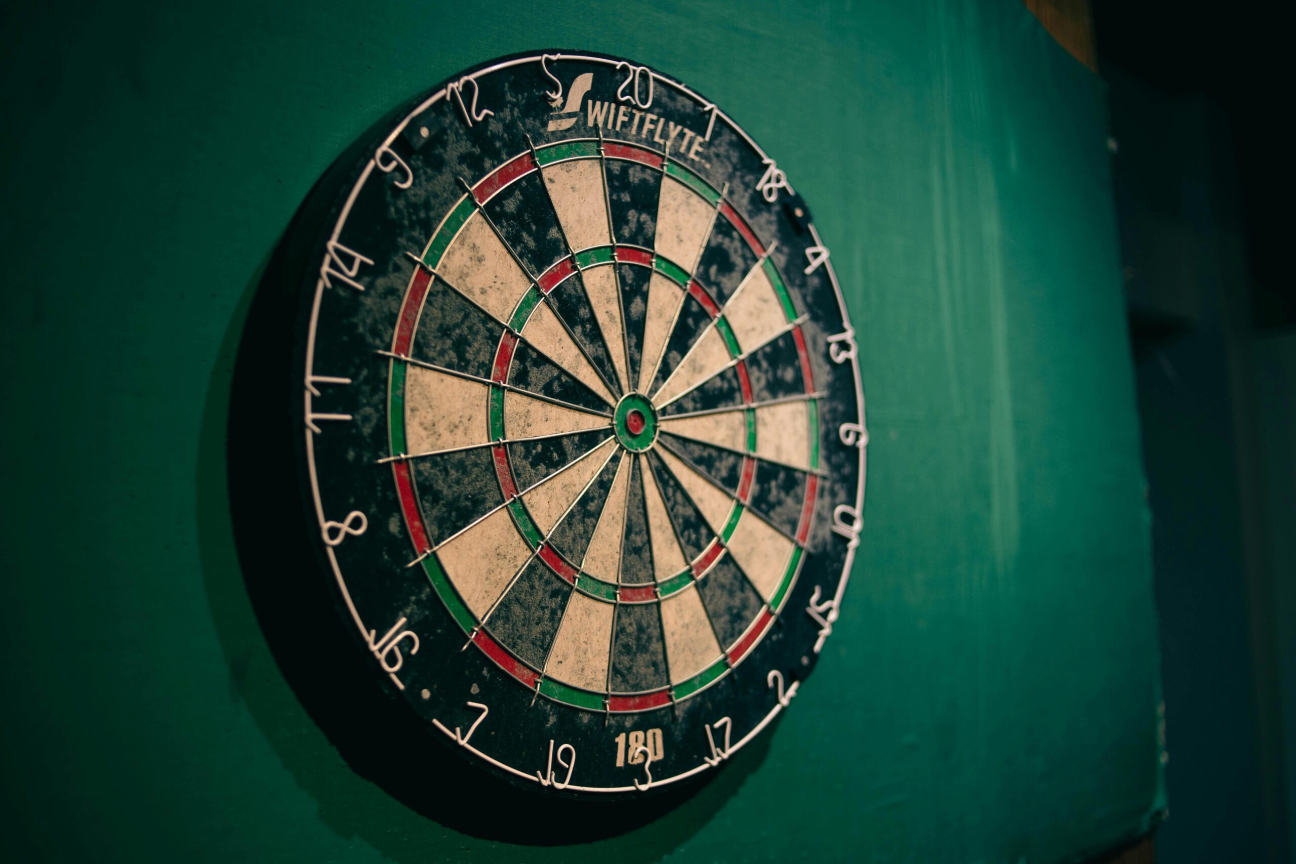 A dart board on a green wall.