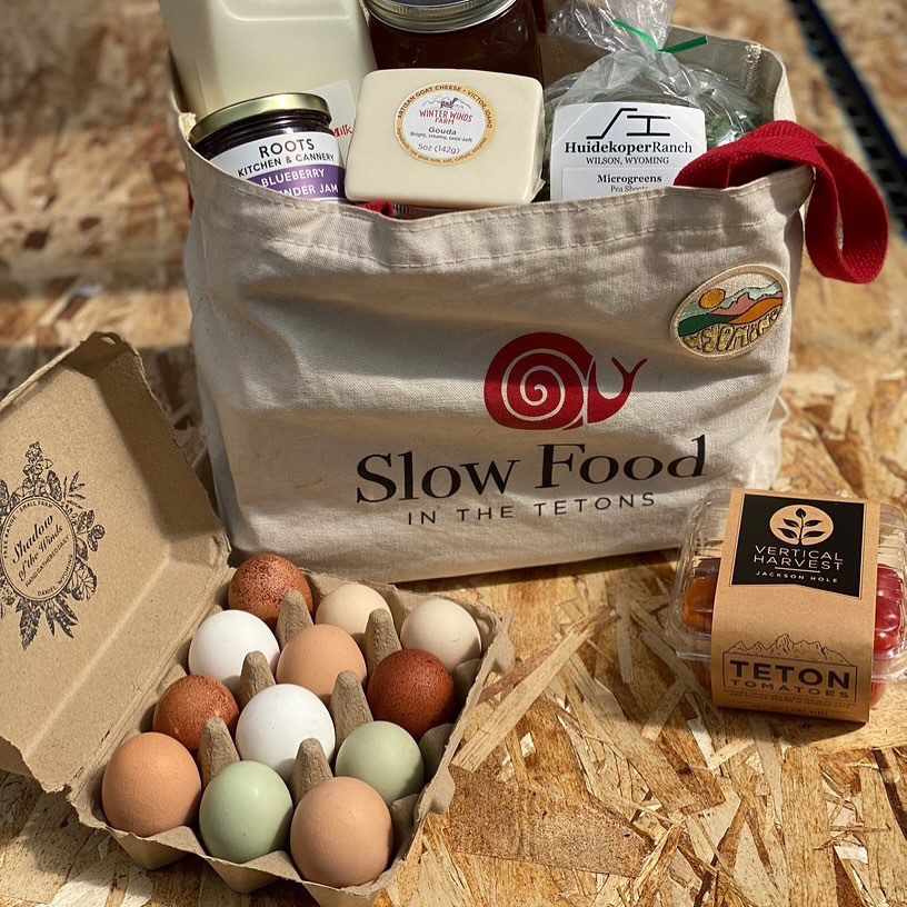 A canvas grocery bag filled with provisions, next to a carton of eggs.