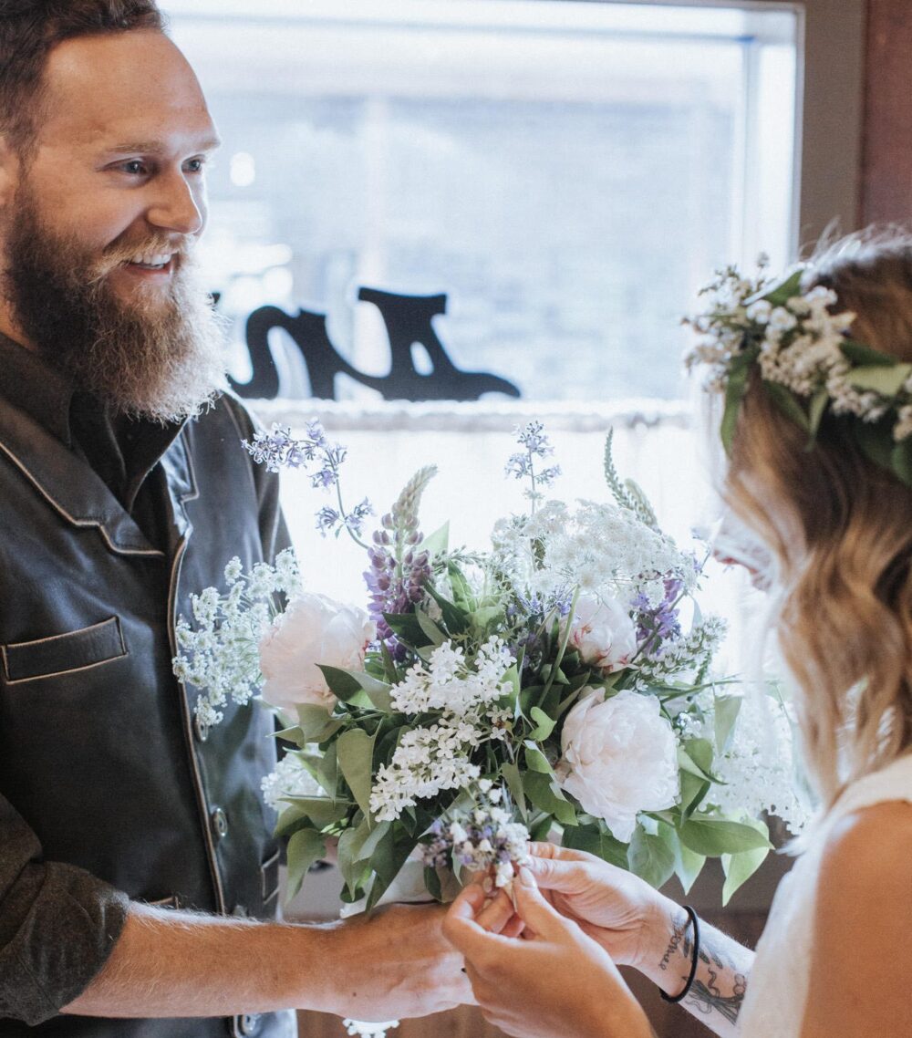 A bride and groom exchanging rings in the Anvil Hotel lobby, with a beautiful bouquet.