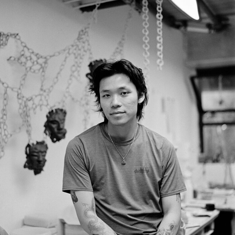 A black and white photo of artist Sheldon Wong in his studio.