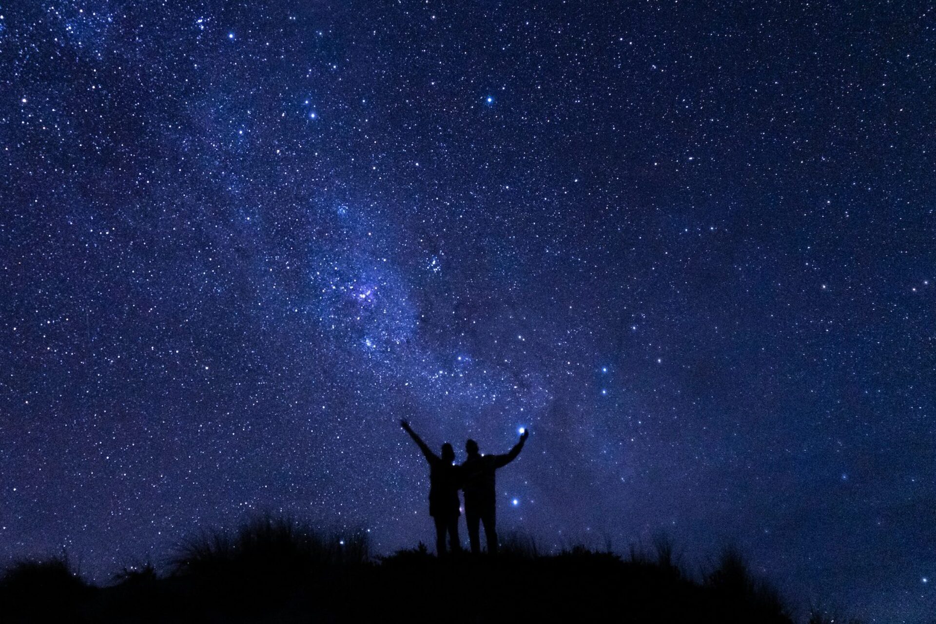 A sky full of stars with two people in shadow.
