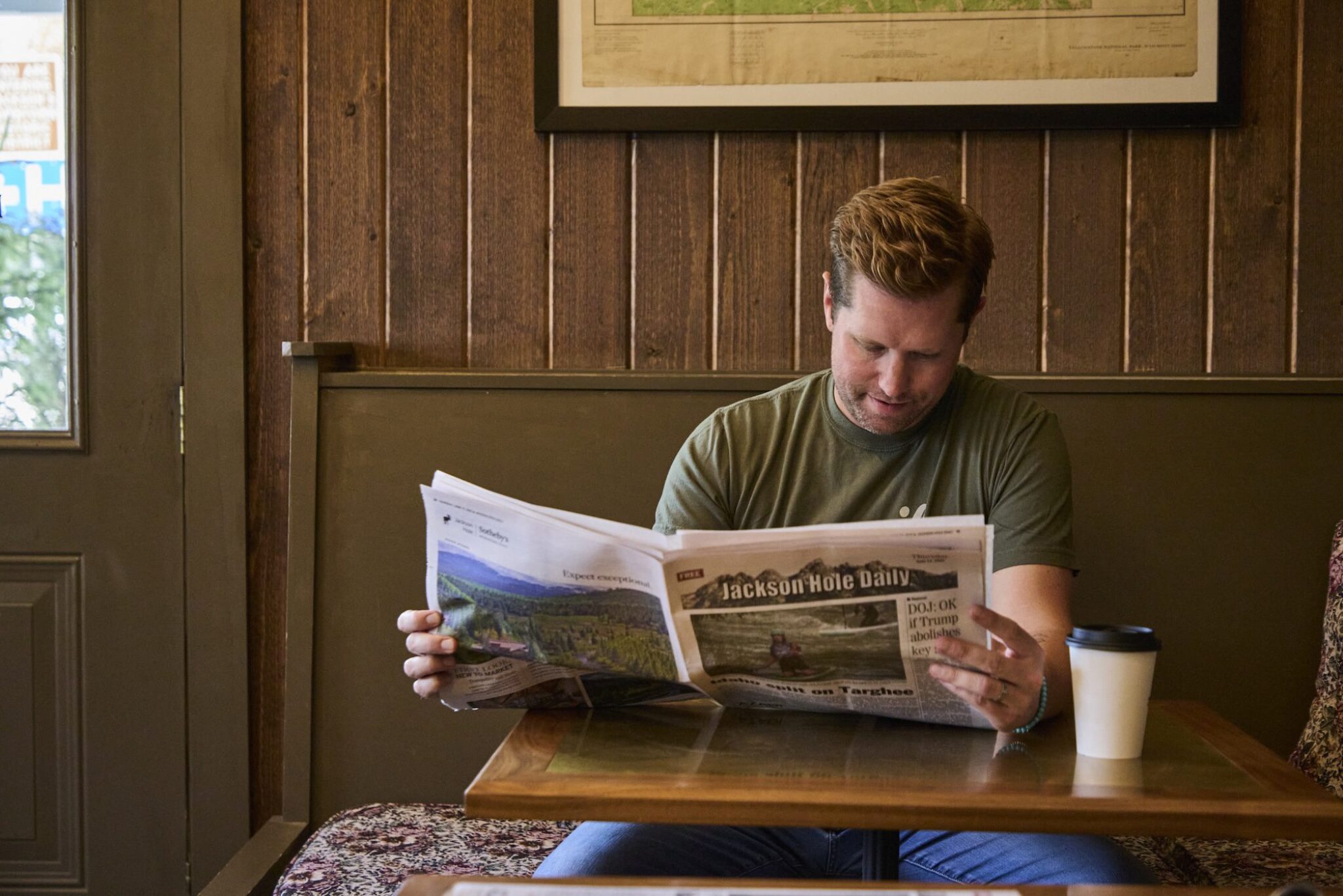 A man reading a newspaper in the lobby of Anvil Hotel in Jackson.