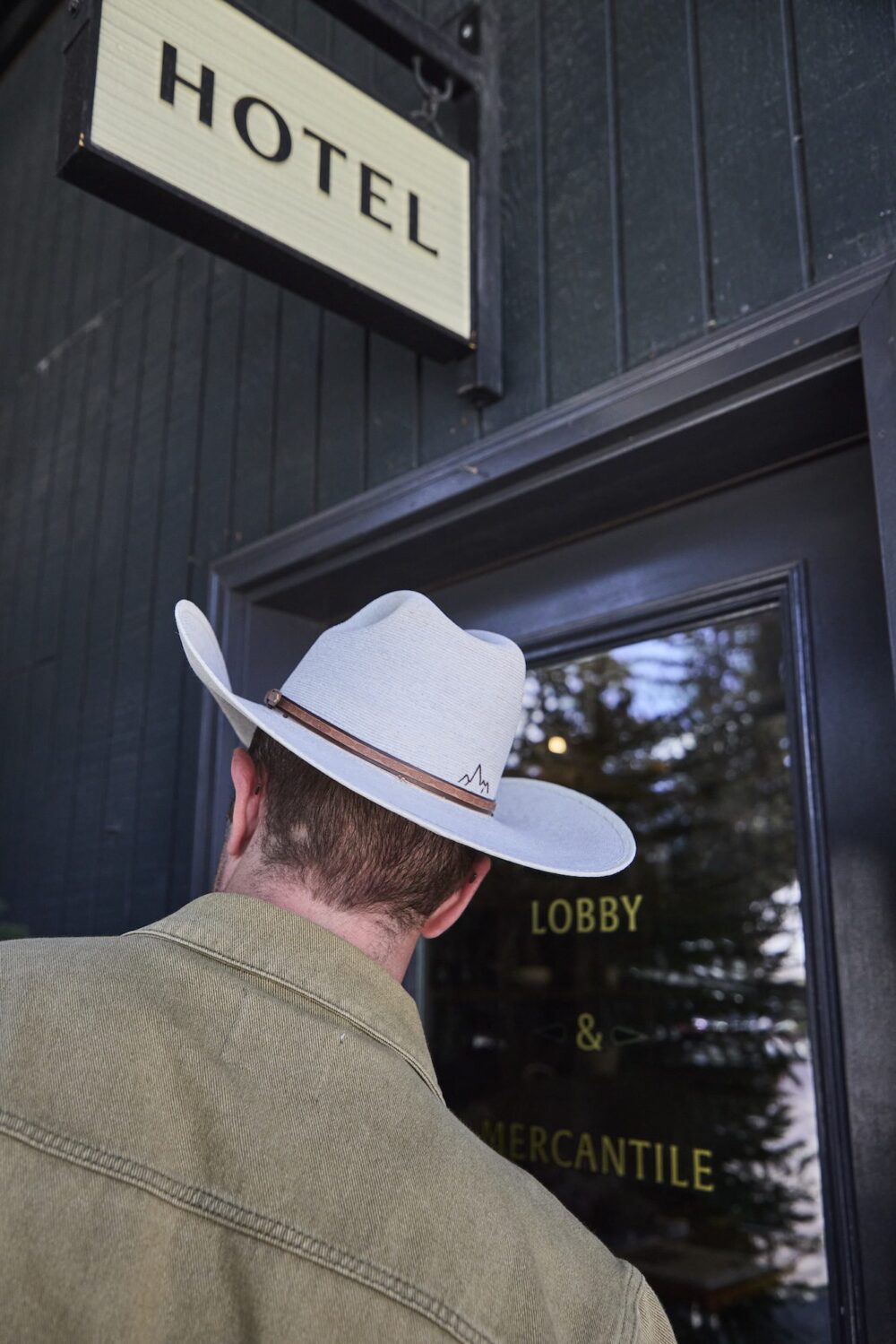 A man with a Stetson hat walking into the lobby of Anvil Hotel.